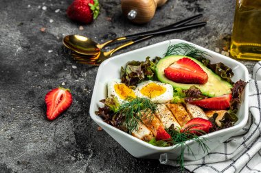 Keto kahvaltısı iki yumurta, avokado, çilek, ızgara tavuk fileto, fındık ve taze salata, ketogenik diyet. Keto diyet yemekli tabak. Sağlıklı gıda konsepti, üst görünüm.