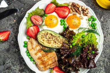 Sağlıklı besleyici paleo keto kahvaltı diyeti kızarmış yumurta, avokado, ızgara tavuk fileto, fındık, çilek ve taze salata. Keto kahvaltısı ya da öğle yemeği. en üstteki görünüm,