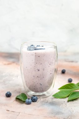 blueberry yoghurt shake in glass jar on a light background, place for text, top view,