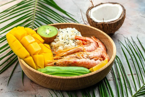 Poke bowl with avocado, shrimp, rice, mango, kiwi and coconut on a light background, healthy and balanced food. banner, menu recipe place for text, top view.