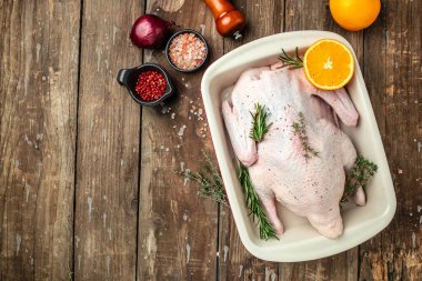 Raw free range duck with spices ready to cook on a wooden background, Culinary cooking. banner, menu, recipe place for text, top view,