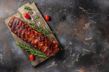 grilled ribs on cutting board on a dark background. American Spare Ribs in BBQ Sauce. Restaurant menu, dieting, cookbook recipe top view.