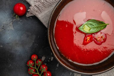 Arka planda fesleğenli püre domates çorbası. Temiz yemek, diyet, vejetaryen yemek konsepti. en üstteki görünüm.