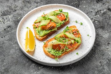 Tuzlu somon, avokado ve taze sebzeli sandviç. Lezzetli kahvaltı ya da atıştırmalık, temiz yemek, diyet, vejetaryen yemek konsepti. en üstteki görünüm