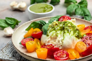 Domatesli salata, Burrata peyniri ve açık arkaplanda yeşil pesto. afiş, menü, metin için tarif yeri, üst görünüm.