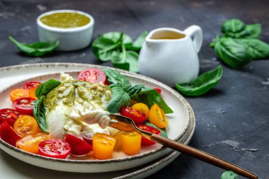 Burrata peynirli salata, vişneli domates ve koyu arkaplanda yeşil pesto. Restoran menüsü, diyet, yemek tarifi üst hayat.