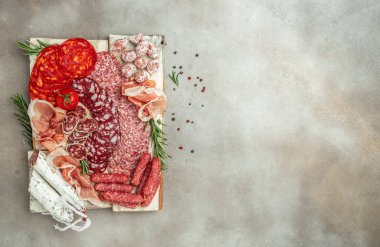 Antipasto tabağı. Prosciutto, pastırma, salam ve sosis ahşap bir tahtanın üzerinde. Yemek, pankart, menü, yemek tarifi. metin için yer, üst görünüm.