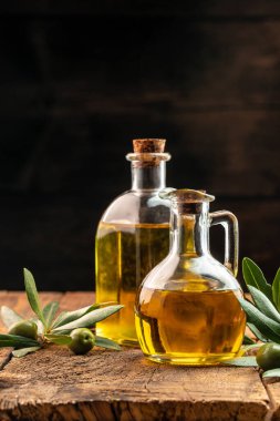 Zeytin ve yağ. Ahşap arka planda ekstra saf zeytinyağı kavanozları. dikey görüntü. metin için yer.