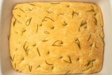 Fırın kabında odaklanma. Siyah arka planda biberiyeli geleneksel İtalyan Focaccia 'sı. afiş, menü, metin için tarif yeri, üst görünüm.