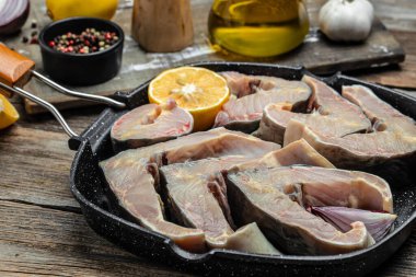 Ahşap bir arka planda ızgara tavada mersin balığı bifteği.