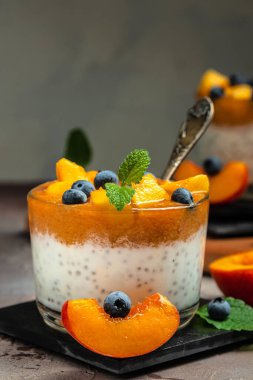 yogurt dessert with peaches blueberry chia on a dark background. Natural detox, fruit dessert, healthy dieting concept.