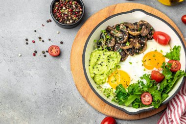 Avokado ve mantarlı sahanda yumurta yakın plan. Ketogenik diyet. Düşük karbonhidratlı yüksek yağlı kahvaltı. Sağlıklı gıda konsepti. metin için yer, üst görünüm,