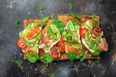 Krem peynirli sandviç seti, prosciutto, somon, avokado ve taze yeşillik. Keto, ketojenik diyet, düşük karbonhidrat, yüksek yağ, sağlıklı yiyecekler. en üstteki görünüm.