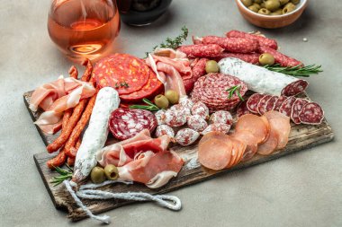 Antipasto meat board. catering platter with bacon, jamon, sausage and wine. Food recipe background. Close up.