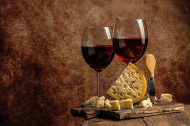 Tahta bir arka planda peynir ve şarap. Büyük delikli maasdam ya da Emmental. metin için yer.