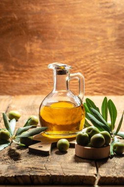 Siyah ve yeşil zeytinli ve yapraklı şişelerde zeytin yağı. Ahşap arka planda ekstra saf zeytinyağı kavanozları. dikey görüntü. Üst Manzara. metin için yer.