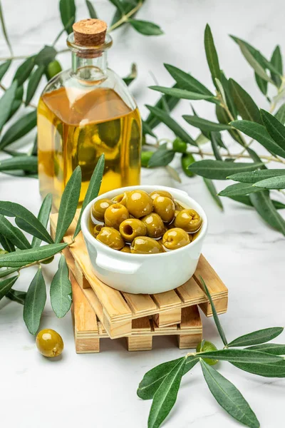 Branch with olives and a bottle of olive oil on white background. top view. place for text,