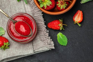 Jar of strawberry jam on dark background. Homemade strawberry marmelade and fruits. Long banner format.