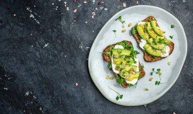 Sağlıklı avokado tostları, çavdar ekmeği dilimlenmiş avokado, peynir, balkabağı, fındık ve susamlı kahvaltı ya da öğle yemeği. Vejetaryen yemeği. Vejetaryen menüsü. Yemek tarifi.