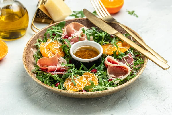 winter salad with arugula mandarins, prosciutto jamon and Parmesan cheese. place for text, top view.