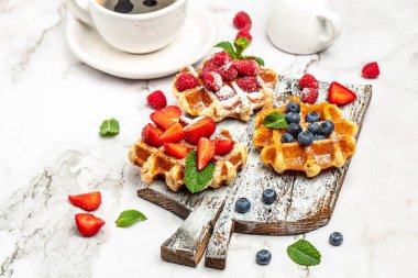 Beyaz arka planda taze meyve ve karamel ile geleneksel Belçika waffleları. Düz konum, üst görünüm, kopyalama alanı.