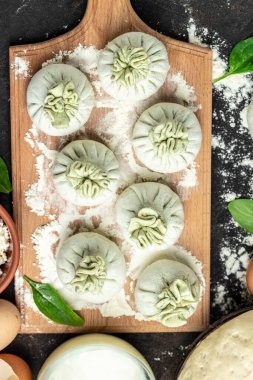 Peynirli ve ıspanaklı Khinkali. Çiğ, yarı bitmiş meyveli börekler. Khinkali pişirmek. Ulusal Gürcü mutfağı. afiş, menü, metin için tarif yeri, üst görünüm.