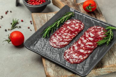 Thinly sliced salami or dry sausage on black plate. Restaurant menu, dieting, cookbook recipe top view.