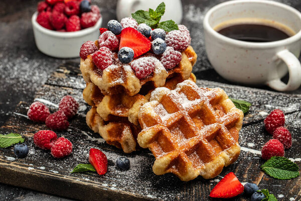Belgian Waffles sweet desert with raspberries, strawberries and blueberries, sugar powder.
