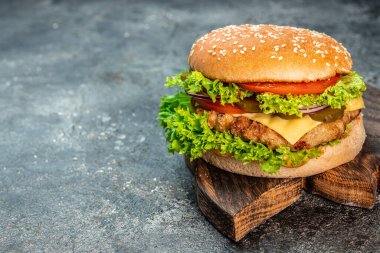 Sığır eti, domates, peynir, pastırma ve marullu ev yapımı leziz ızgara burger. Fast food ve abur cubur kavramı.