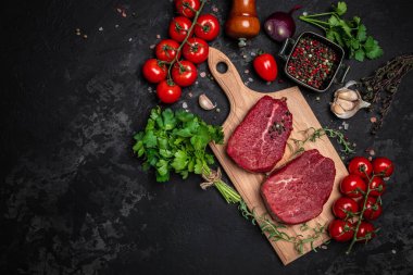 Biberiyeli sığır filetosu ve koyu arkaplanda baharatlar. Pişirmeye hazır taze biftek hazırlıyorum, uzun pankart formatında. en üstteki görünüm.