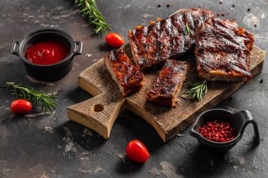Barbecue pork spare ribs on a dark background. American Spare Ribs in BBQ Sauce. Restaurant menu, dieting, cookbook recipe top view.