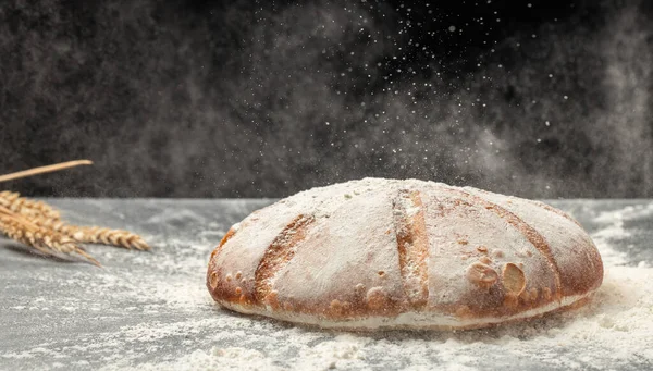 Homemade sourdough bread with powder in a freeze motion of a cloud of powder midair. Culinary, cooking, bakery concept.