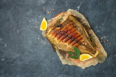 Baked Flounder Fish with lemon and spices on a dark background. banner, menu, recipe place for text, top view.