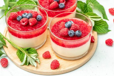 İtalyan tatlısı. Hafif arka planda ahududu reçelli ahududu panna cotta. Küçük kavanozlarda krema soslu böğürtlen tatlısı. Uzun afiş biçimi. metin için yer.