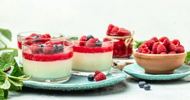 Hafif arka planda ahududu reçelli ahududu panna cotta. Küçük kavanozlarda krema soslu böğürtlen tatlısı. metin için yer.