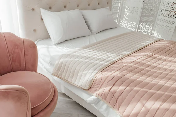 Big comfortable bed with clean linen in room, bed linen pillows blankets pink pastel colors. cleaning Ironing,