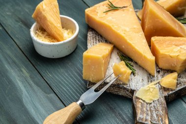 Parmesan peyniri dilimlenmiş ve rendelenmiş. Tahta arka planda bıçaklı bir parmesan peyniri seti. Uzun afiş biçimi. en üstteki görünüm.