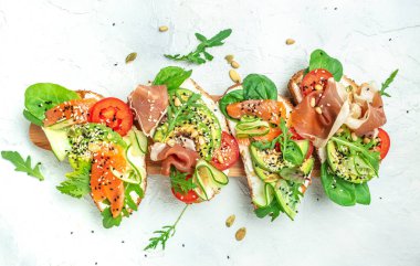 Krem peynirli sandviç seti, prosciutto, somon, avokado ve taze yeşillik. Keto, ketojenik diyet, düşük karbonhidrat, yüksek yağ, sağlıklı yiyecekler. en üstteki görünüm.