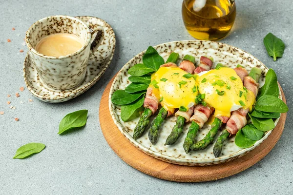 stock image Delicious breakfast with eggs Benedict and green asparagus wrapped in grilled bacon and a cup of coffee. banner, menu, recipe place for text, top view.