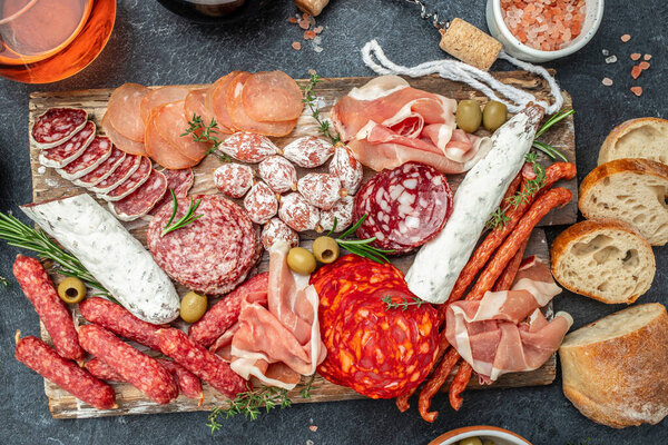 Salami, sliced ham, sausage, prosciutto bacon, toasts, olives. Meat antipasto platter and red wine, Food recipe background. Close up,