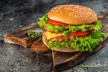 Sığır eti, domates, peynir, pastırma ve marullu ev yapımı leziz ızgara burger. Fast food ve abur cubur kavramı.