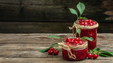 Bir kavanoz kiraz reçeli ve ekşi kiraz. Şerbetli kiraz. Olgun kirazlar. Tatlı kırmızı kirazlar. Ahşap bir arka planda konserve meyve.