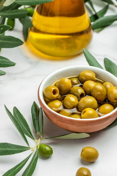 Branch with olives and a bottle of olive oil on light background. top view. place for text.