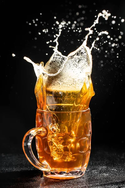 stock image glass of splashing beer. Freeze motion splash drops of beer foam.