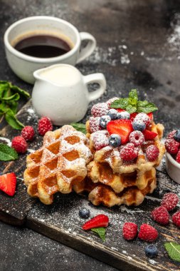 Süt sürahisi ile servis edilen bir toz bulutunun dondurucu hareketinde şekerli ahududulu Belçika waffleları. Lezzetli kahvaltı ya da atıştırmalık.