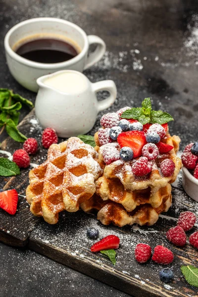 Belgian waffles with raspberries with sugar powder in a freeze motion of a cloud of powder midair, served with jug of milk. Delicious breakfast or snack.