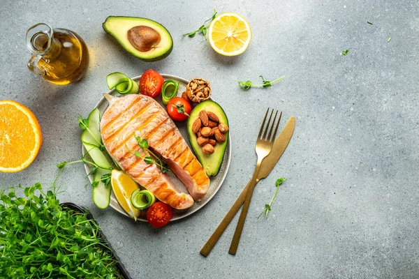 Dish grilled salmon steak with avocado and fresh vegetable salad. Keto diet concept healthy food, Healthy fats, clean eating for weight loss. top view.