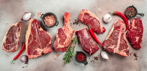 Black angus prime meat set for grilling with fresh herbs, spices. Long banner format. top view.