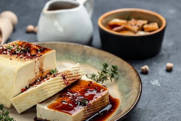 marinated tofu with herbs and spices. vegetarian tofu cubes on a dark background. banner, menu, recipe place for text, top view.