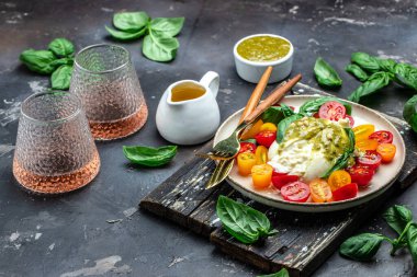 Burrata cheese with tomatoes and green pesto. Vegetarian italian food. Food recipe background. Close up.